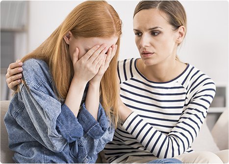 crying young woman consoled by woman counsellor