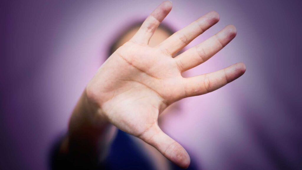 Addiction and domestic violence: an outstretched hand covering someone's face.