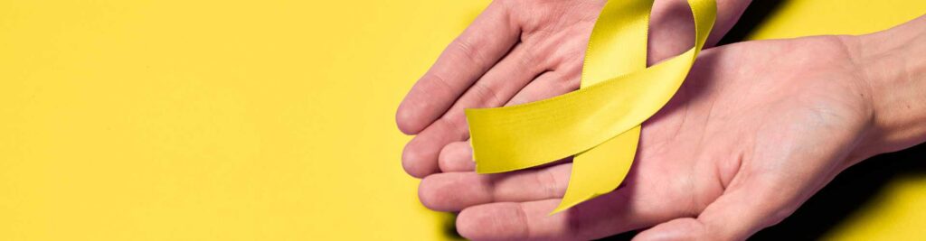 Hands holding a yellow ribbon to signify World Suicide Prevention Day.
