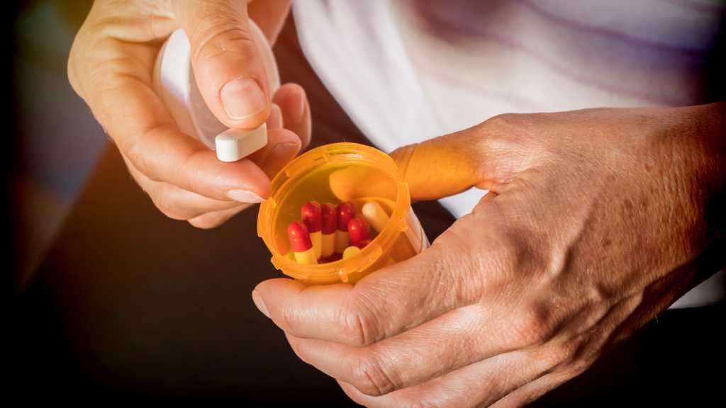Hand holding a prescription bottle with medication used in medication-assisted treatment for opioid addiction and recovery support.