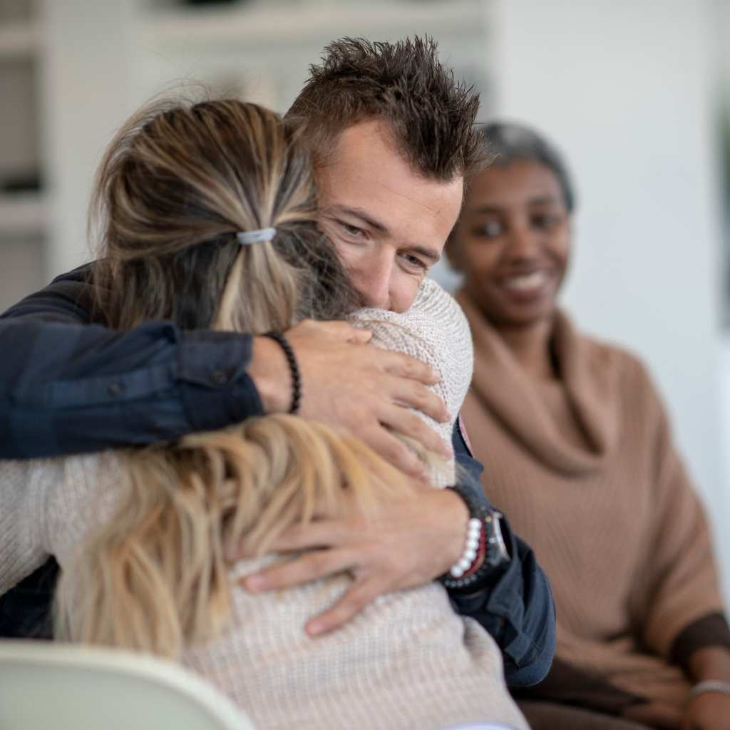 Two people sharing a comforting hug in an IOP program recovery meeting