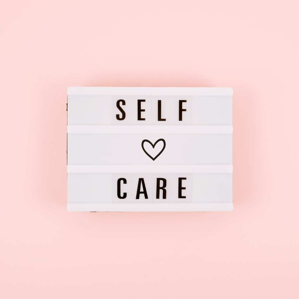 White lightbox on a soft pink background with the words self care